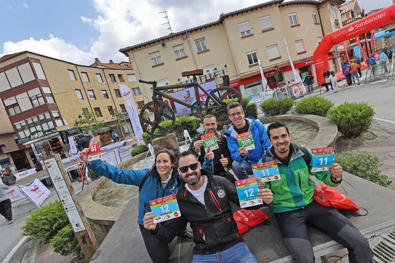 Varios participantes, con sus dorsales en el monumento a la bicicleta, junto a la línea de salida y meta de Los 10.000 del Soplao