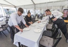 Personal de hostelería preparando una terraza de comedor en un establecimiento en Santander.