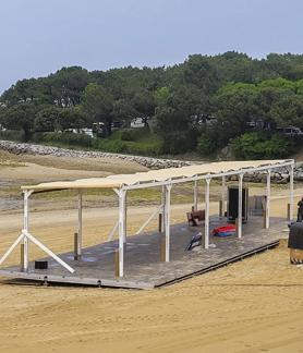 Imagen secundaria 2 - En la imagen de la izquierda, las carpas que han instalado en la carretera paralela a la playa. En la de la derecha, la plataforma sobre la que se grabará el programa.