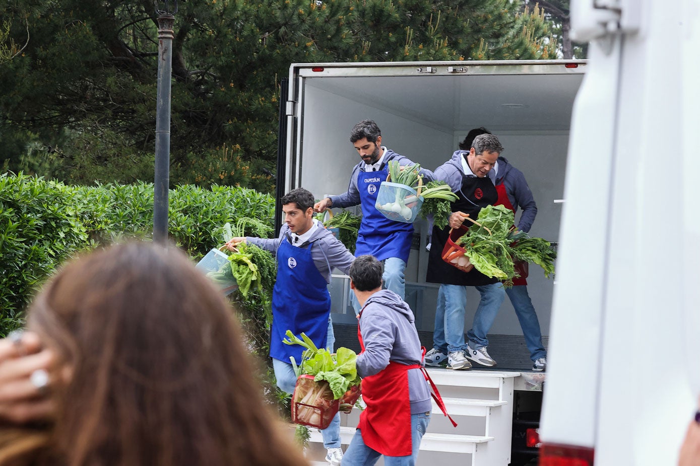 Varios de los concursantes bajando de los camiones la comida con la que iban a cocinar.