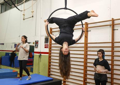 Imagen secundaria 1 - Una alumna realiza acrobacias en el trapecio, ante la mirada y el apoyo de sus compañeras de clase. A la derecha, la complicidad entre estudiantes y docentes genera un tándem perfecto de disciplina y juego.