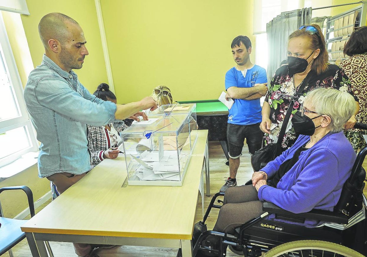 Una vecina se dispone a votar en el Centro Cívico Social Pedro Lázaro Baruque, este domingo, en el barrio de La Inmobiliaria (Torrelavega).