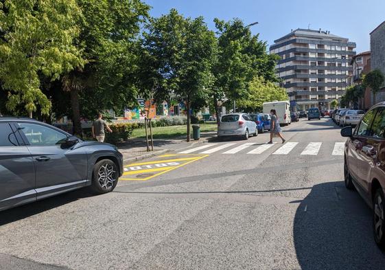 Una vecina cruza un paso de peatones delimitado por uno de los nuevos aparcamientos para motos.