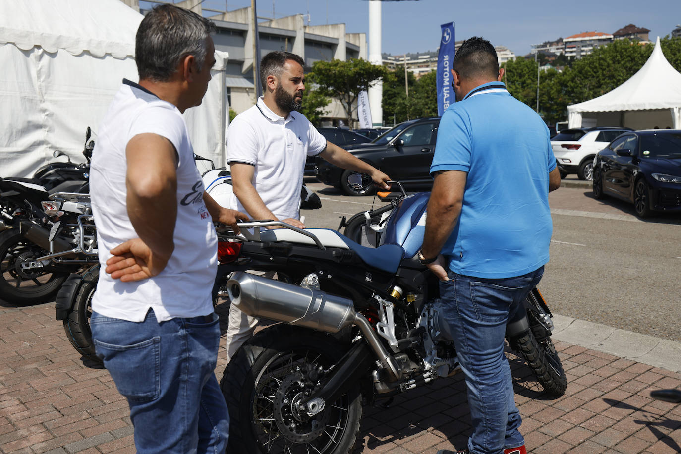 Un vendedor explica las características de una moto a unos posibles clientes.