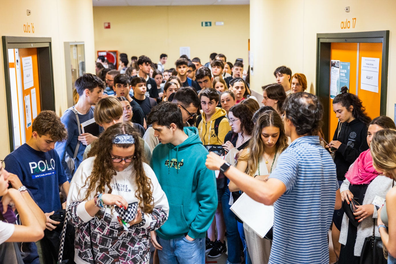 El responsable de una de las aulas llama a los estudiantes, que tienen que mostrar su documentación para comprobar su identidad antes de acceder a la clase.