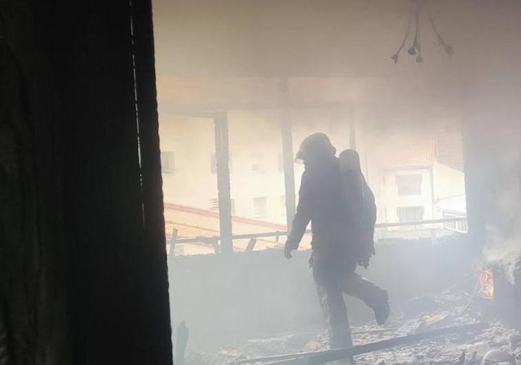 Uno de los bomberos en el interior de la vivienda que ha quedado totalmente calcinada.