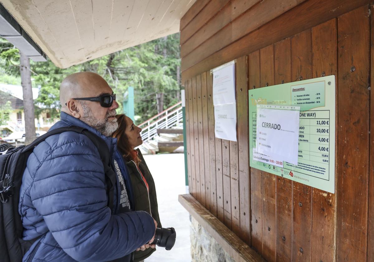 Una pareja, en las taquillas del teleférico, lee el cartel en el que se informa del cierre de las instalaciones.