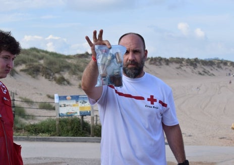 Imagen secundaria 1 - Arriba los voluntarios escuchan al coordinador de Cruz Roja y técnico ambiental Javier Cacho, al que se le puede ver debajo portando una bolsa de basura, y sobre estas líneas un voluntario en acción detectando residuos. 