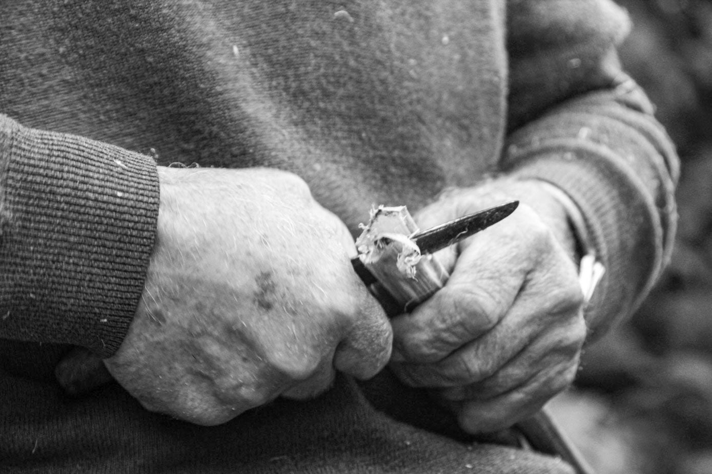 Un hombre parte la madera con una navaja.