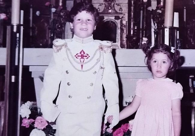 Agustín, con traje de gala en su Comunión, coge de la mano a su hermana Verónica.