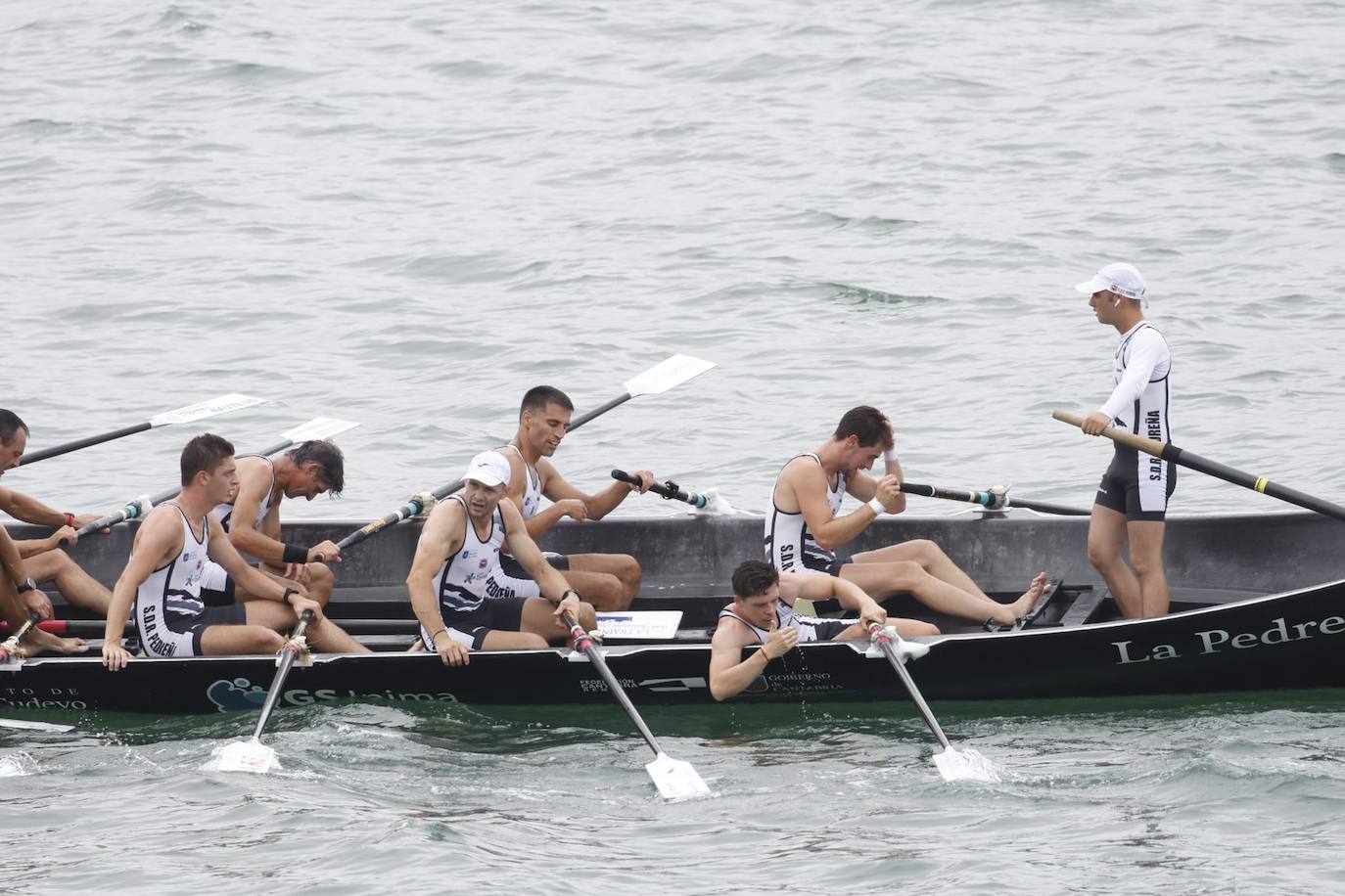 Imagen secundaria 1 - Remeros, técnicos y directivos de Camargo celebran el título en Laredo. Debajo, la tripulación de Pedreña al final de la regata.