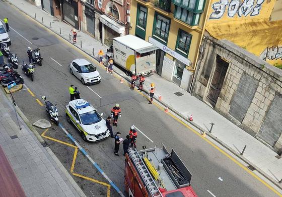 El camión, incrustado en la acera, y efectivos de la Policía y los Bomberos tratando de solventar la situación.