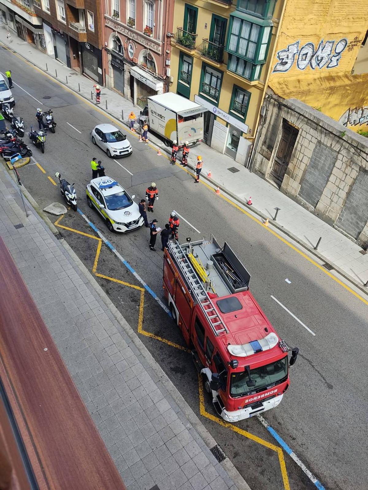 El camión, incrustado en la acera, y efectivos de la Policía y los Bomberos tratando de solventar la situación.