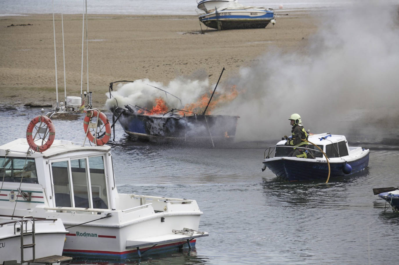 Uno de los bomberos participantes se dispone a regar con agua el barco en llamas. 