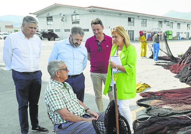 PP. De pesca en Colindres. Elena Castillo, Alejandro Liz, Javier Noriega y Severiano Cuesta charlan con un hombre que trabaja en las redes tras reunirse con representantes de la cofradía.