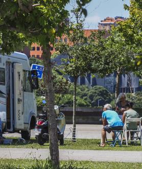 Imagen secundaria 2 - 1. Autocaravanas aparcadas en prados de Oyambre. | 2. Un grupo de usuarios sentados junto a una autocaravana en las proximidades de Las Llamas.