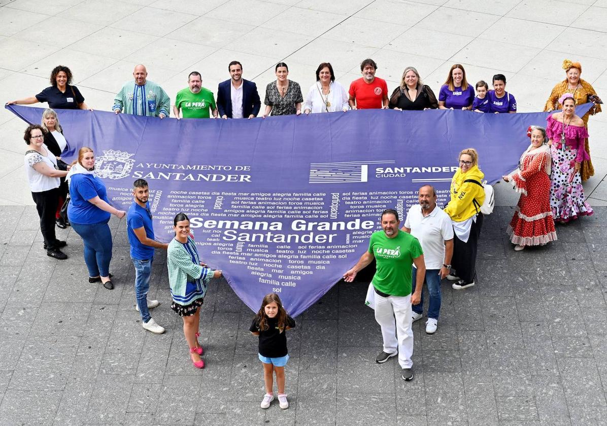 Organizadores de la programación sostienen el pañuelo de las fiestas en la plaza del Ayuntamiento.