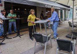 Nely y Pedro retiran una mesa de la terraza del Café Avenida, uno de los establecimientos afectados.