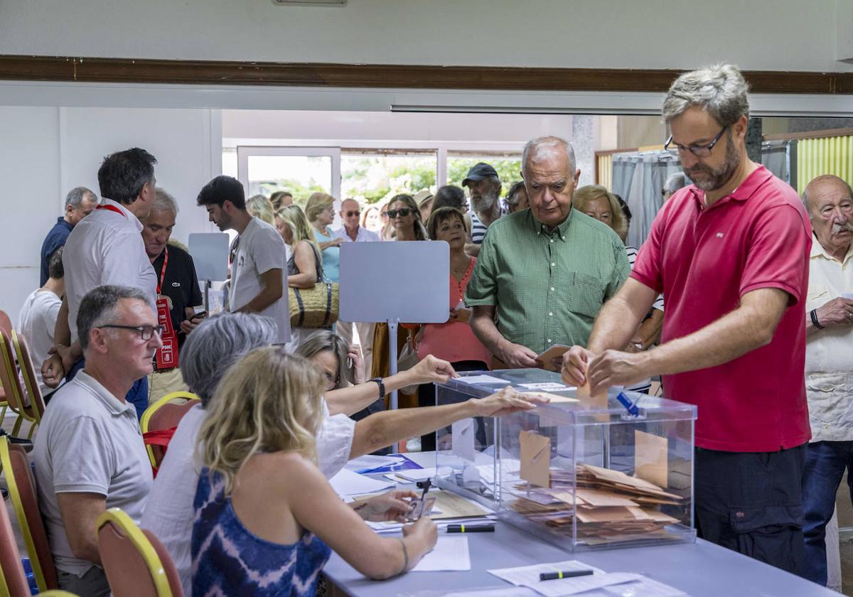 Un vecino, este domingo, introduce el voto en la urna del colegio electoral ubicado junto a la Iglesia de San Roque, en El Sardinero.