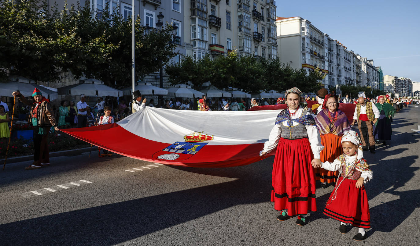 La bandera de Cantabria la sujetan desde los cuatro extremos mujeres y hombres vestidos con los trajes regionales.