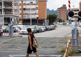 Un vecino cruza la calle Pablo Garnica, una de las vías a renovar, frente al paso a nivel ferroviario, en Torrelavega.