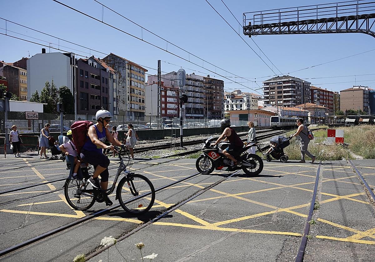 Vecinos cruzan el paso a nivel de Pablo Garnica, junto a la estación de Feve en Torrelavega.