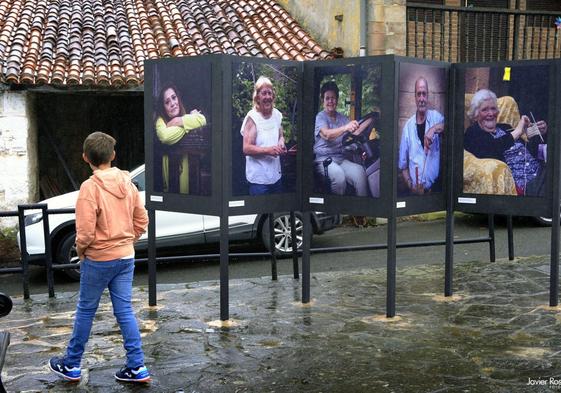 Un niño observa los retratos en la plaza del pueblo de San Vicente del Monte.