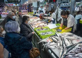 Una pescadera del Mercado de la Esperanza atiende a varios clientes.