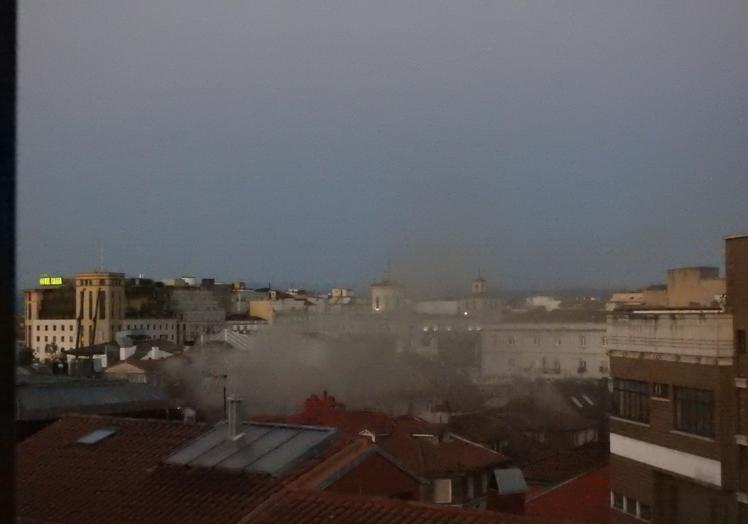 Imagen principal - Arriba, nube de humo sobre la vivienda. Abajo, dispositivo desplegado en pleno centro de la ciudad y de los bomberos accediendo a la vivienda en grúa.