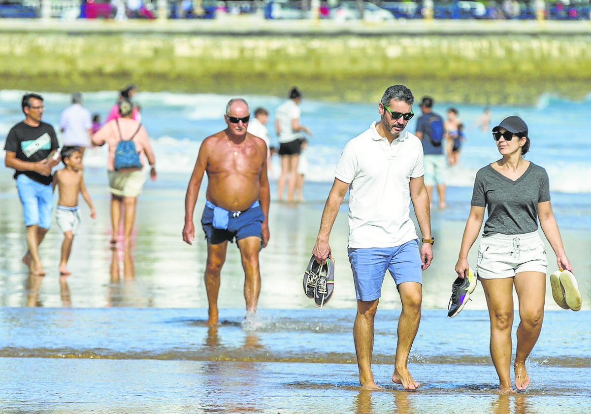 Varias personas caminan por la orilla de la segunda playa de El Sardinero.