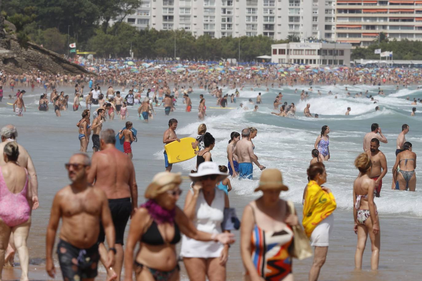 Los bañistas se entremezclan en El Sardinero con los que deciden pasear por la playa.