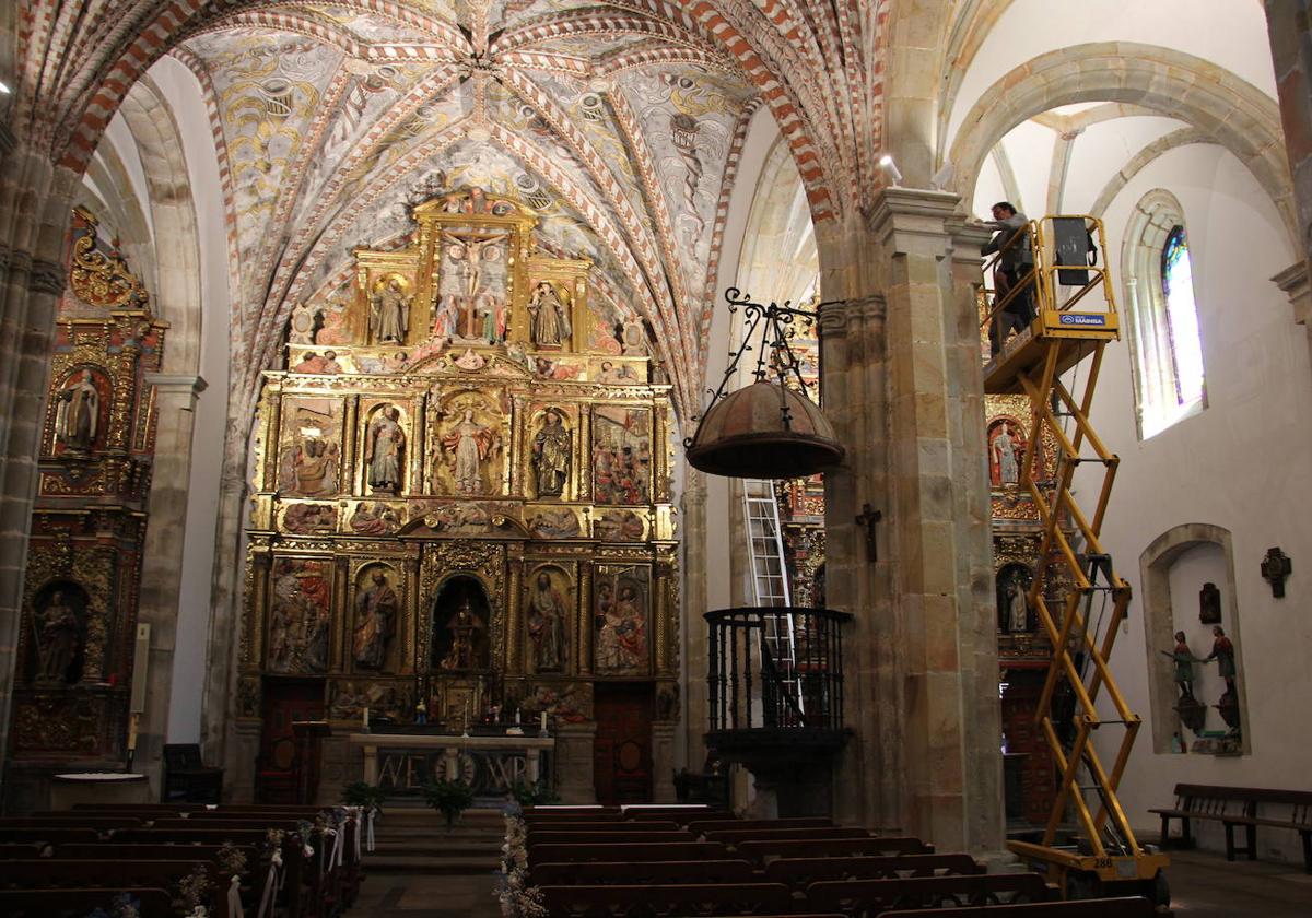 Uno de los operarios, en la grúa, coloca uno de los nuevos focos en el templo.