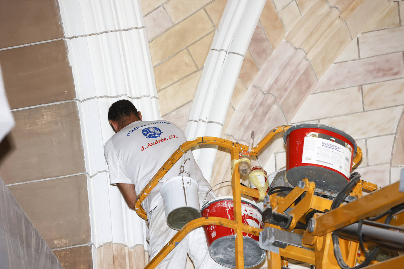 Los trabajadores ejecutan las tareas de pintura desde una grúa, este miércoles, en la iglesia de la Asunción de Torrelavega. 