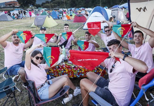 Peñistas muestran sus banderines de fiestas a la cámara, este jueves, desde su campamento en el Bulevar.