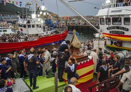 La imagen de la Virgen del Puerto es colocada en el barco Ermita Pilar ante la atenta mirada del público agolpado en el puerto de Santoña.