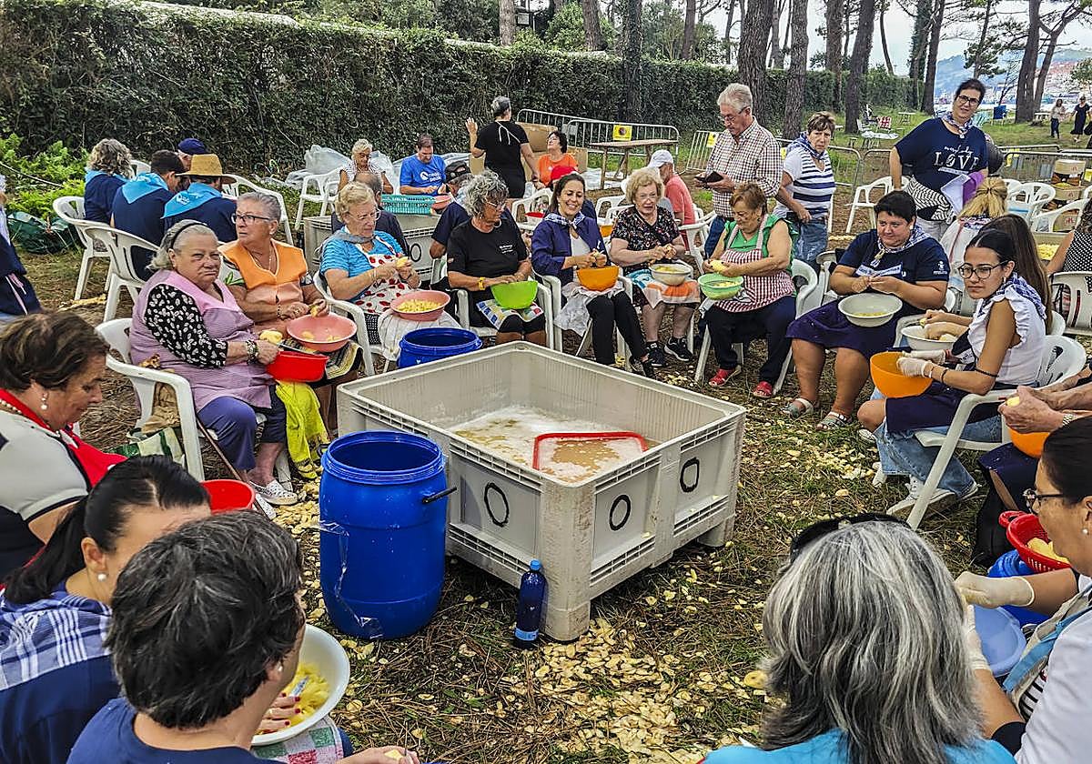 Un numeroso grupo de mujeres pela patatas para preparar el abundante guiso.