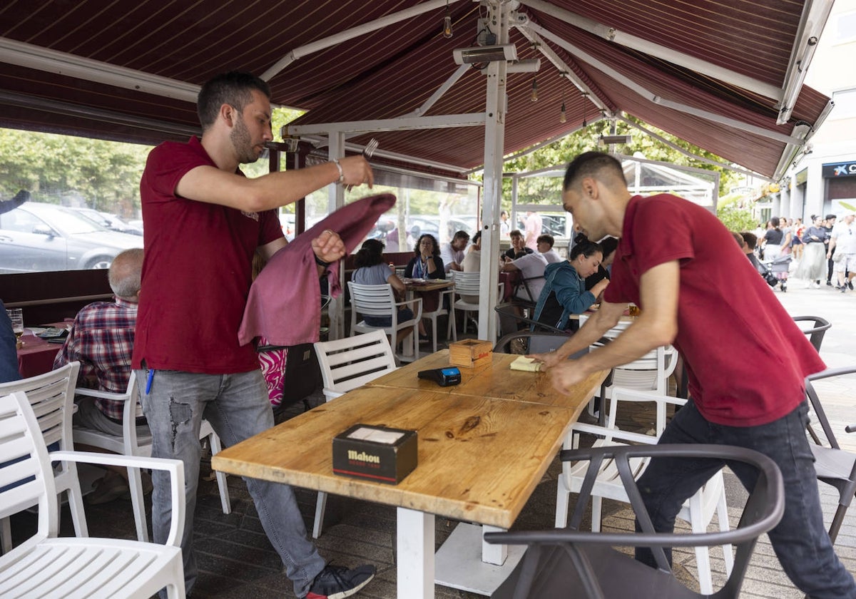 Camareros en Santander, preparando una mesa en una terraza de hostelería.