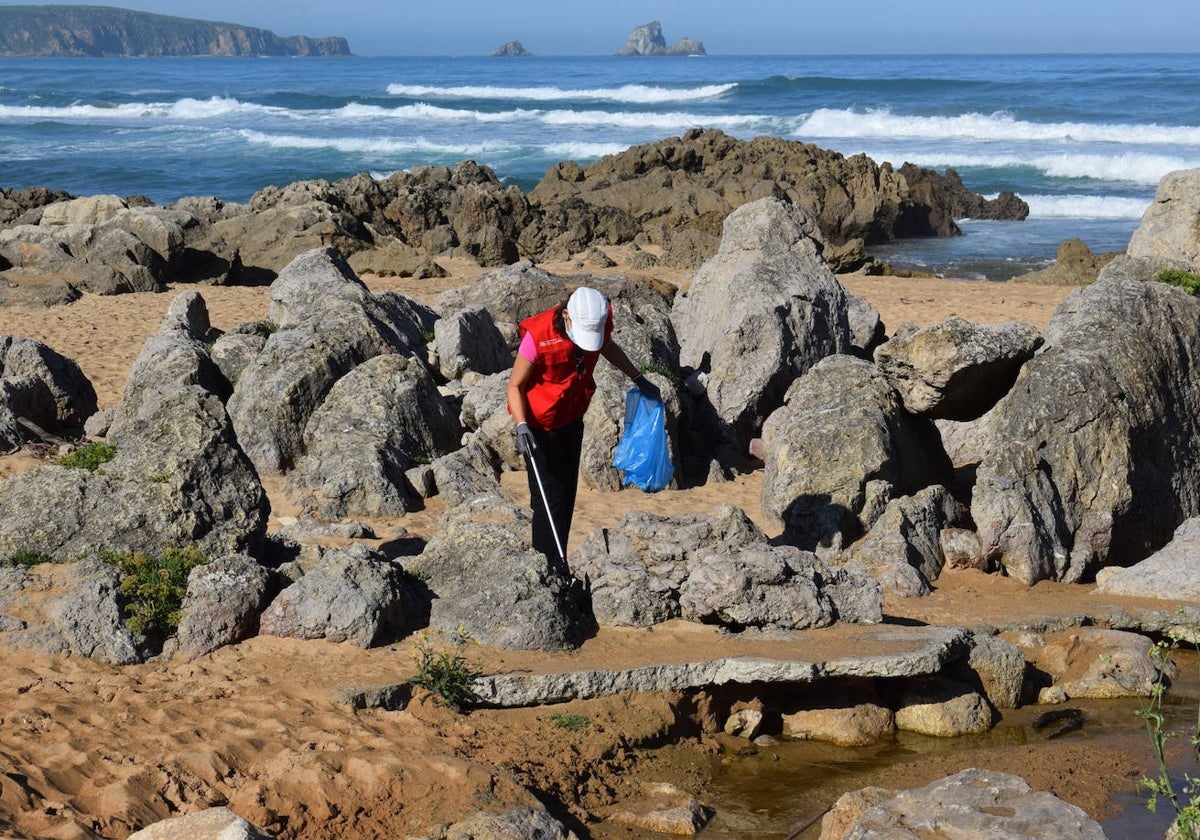 Un voluntario retira basura de la playa de Liencres en una iniciativa anterior.