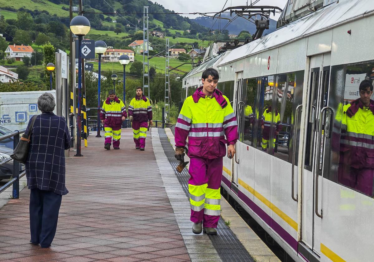 Varios operarios de Adif, en la estación de Heras, pasan junto a un tren averiado en el andén. A cien metros de la estación otro tren había descarrilado.