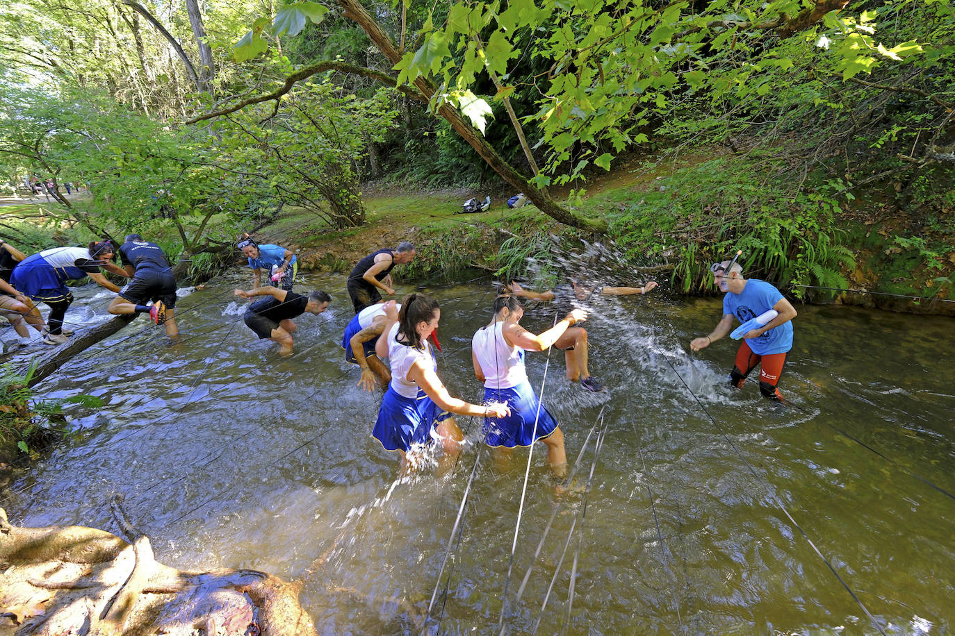 Corredoras tratan de atravesar el río y los obstáculos preparados en él, durante la Katangan Race del Barrio Covadonga.