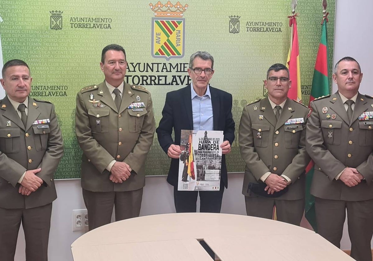 El concejal Pedro Pérez Noriega, en el centro, presenta el cartel del evento flanqueado por los responsables militares, este martes, en Torrelavega.