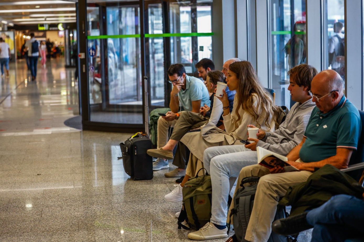 Pasajeros esperan en la sala del aeropuerto, mientras los vuelos siguen cancelados por la niebla. 