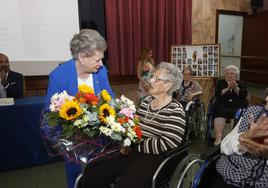 La presidenta del Asilo entrega un ramo de flores a Vicenta Saiz, de 101 años.