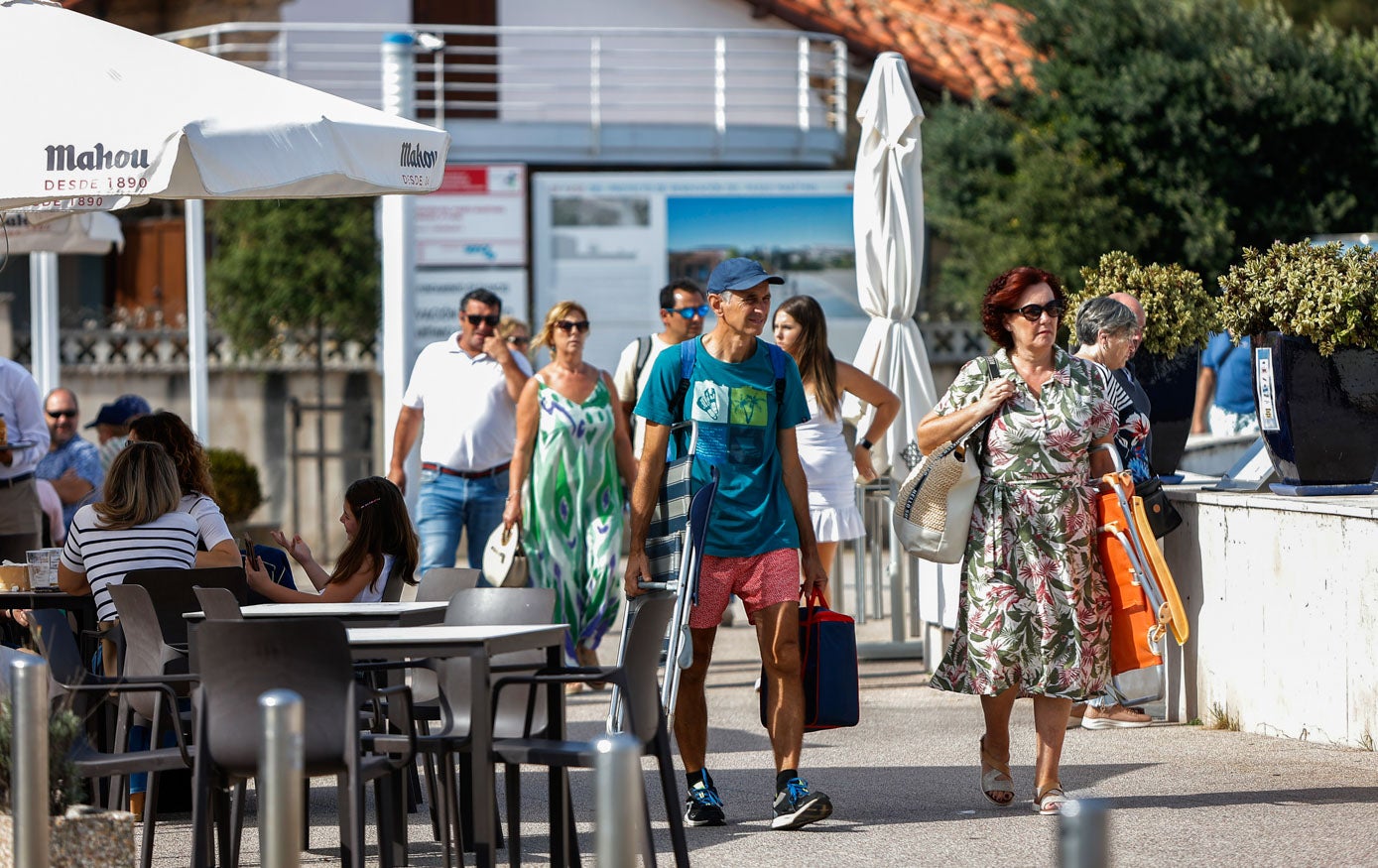 Vecinos y turistas se dirigen a la playa en Suances, mientras otros disfrutan de las terrazas