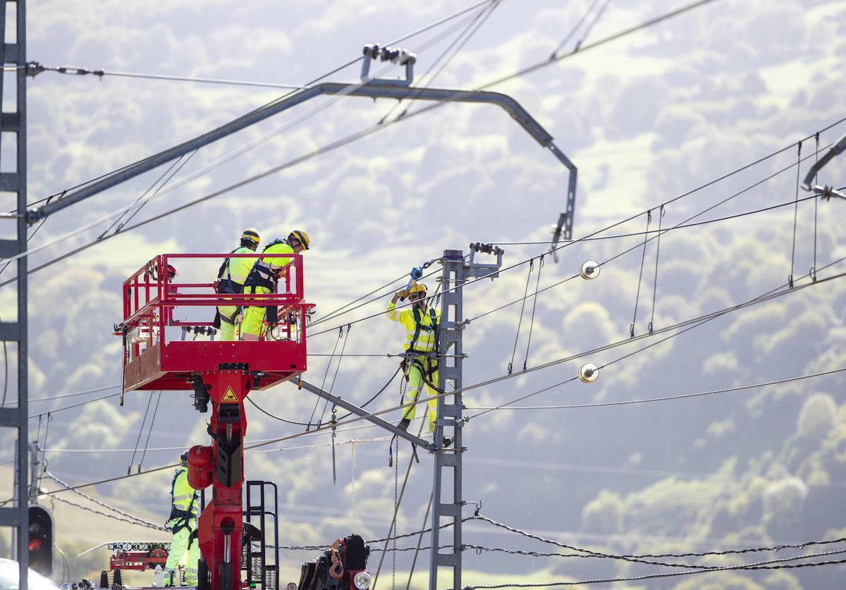 Varios operarios retiran la catenaria para que una grúa pudiera acceder al descarrilamiento de Lantueno.