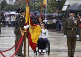 Una mujer en silla de ruedas se dispone a besar la bandera nacional.