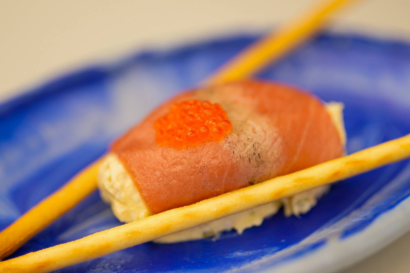 La ensaladilla cubierta por atún rojo y protegida por dos finos palillos.