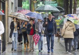 Varios paseantes en el centro de Santander, este sábado, en un día marcado por las lluvias.