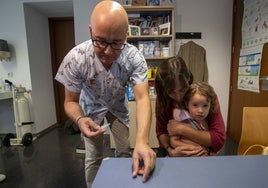 Raúl Ayala, del Centro de Salud Sardinero, prepara la vacuna para la pequeña Jana, en brazos de su madre, Clara.