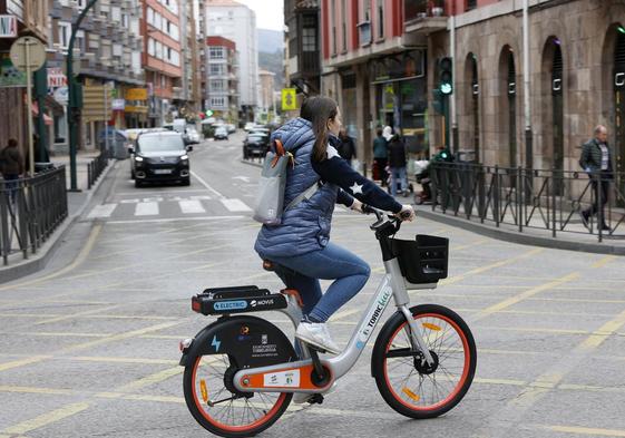 Una joven cruza Cuatro Caminos con una bicicleta eléctrica.